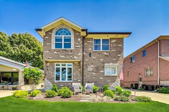 back of property with a yard and brick siding