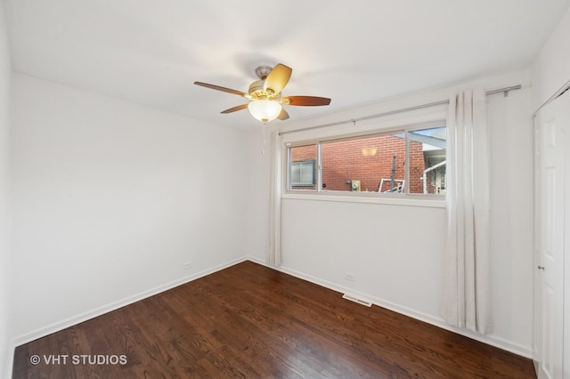 unfurnished room with baseboards, dark wood-type flooring, and ceiling fan