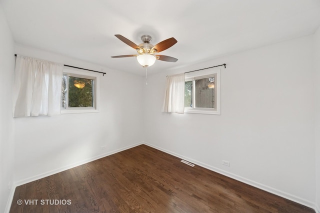 unfurnished room featuring visible vents, baseboards, dark wood finished floors, and a ceiling fan