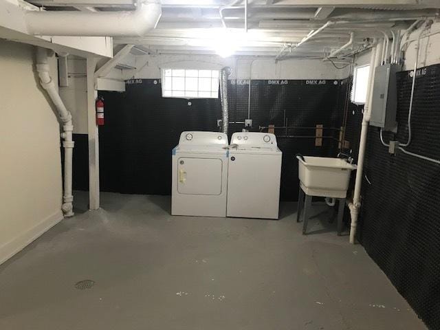 basement featuring a sink, washing machine and clothes dryer, and electric panel