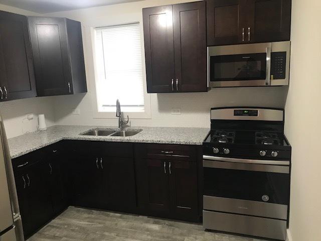 kitchen featuring stainless steel appliances, light stone counters, and a sink