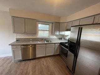 kitchen featuring stainless steel appliances, gray cabinets, a sink, and dark wood-style flooring