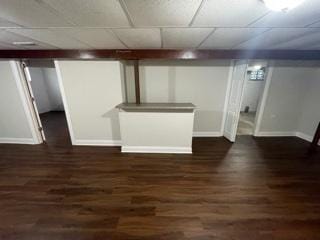 finished basement with a paneled ceiling, baseboards, and wood finished floors