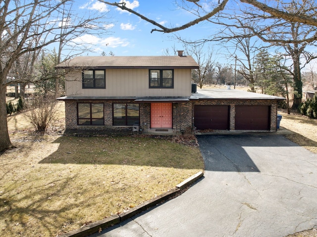 traditional home featuring driveway, a garage, a chimney, a front lawn, and brick siding