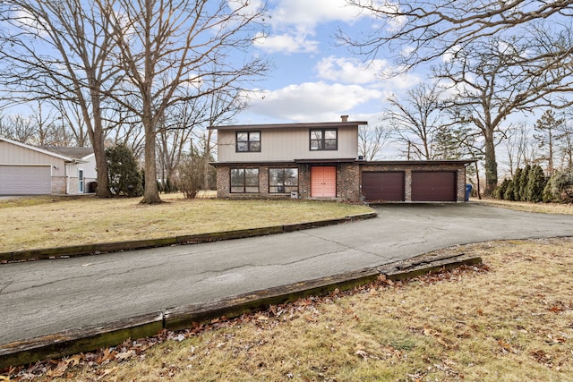 view of front of home with driveway, brick siding, an attached garage, and a front yard