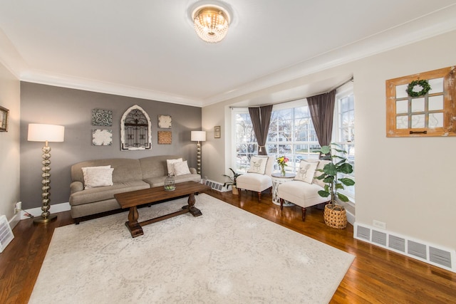 living room featuring baseboards, visible vents, dark wood finished floors, and ornamental molding