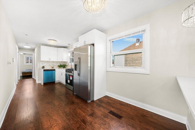457 E 91st St, Chicago, IL 60619 - kitchen featuring appliances with stainless steel finishes, dark wood-type flooring, baseboards, white cabinets, and healthy amount of natural light