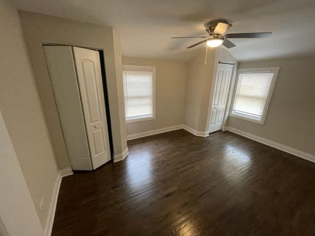 unfurnished bedroom featuring dark wood-style floors, ceiling fan, multiple windows, and baseboards