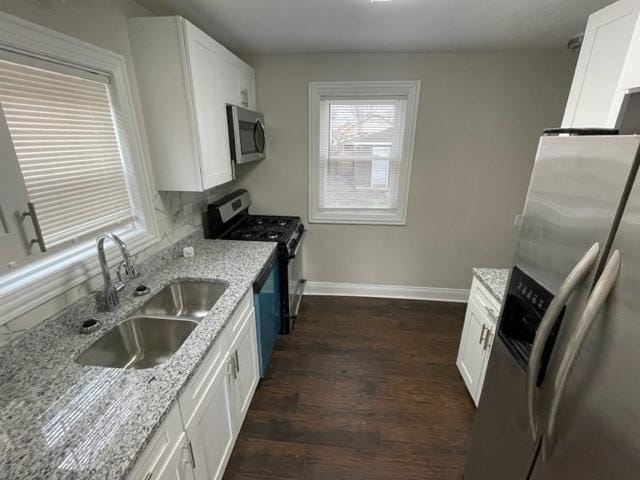 kitchen featuring dark wood-style floors, appliances with stainless steel finishes, white cabinets, and a sink