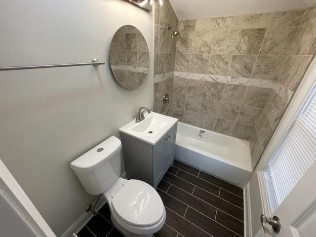 full bathroom featuring baseboards, toilet, vanity, wood finish floors, and shower / washtub combination