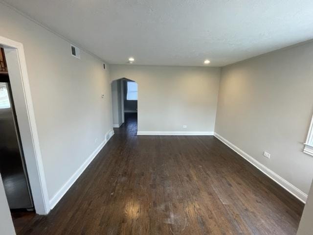 empty room featuring visible vents, baseboards, arched walkways, wood finished floors, and recessed lighting