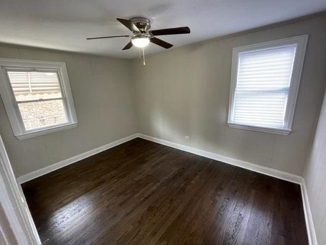 empty room featuring dark wood finished floors, a ceiling fan, and baseboards