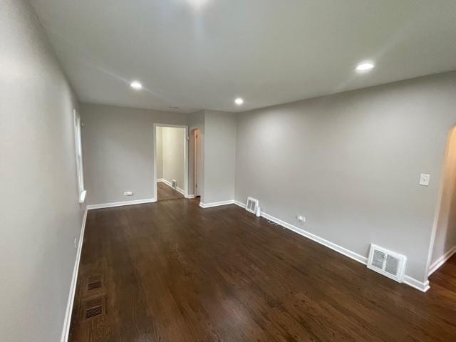 unfurnished room featuring baseboards, visible vents, and dark wood-type flooring