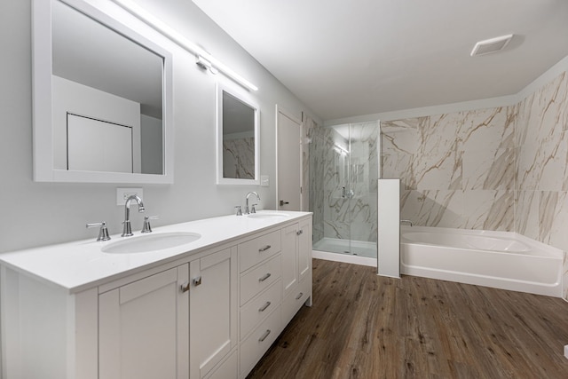 bathroom featuring wood finished floors, a sink, a marble finish shower, and a bath