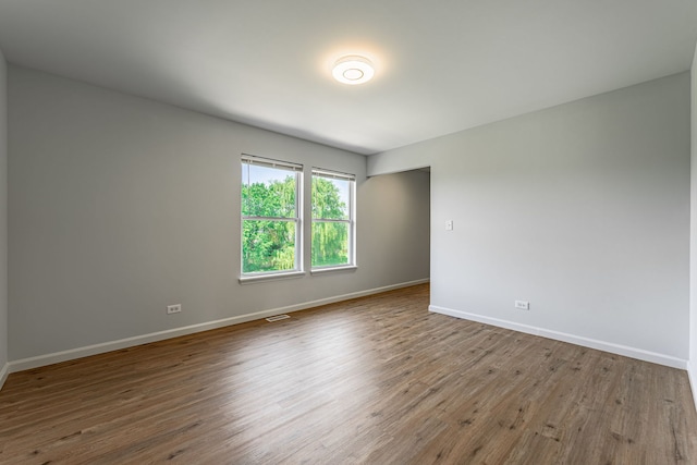 spare room featuring wood finished floors, visible vents, and baseboards