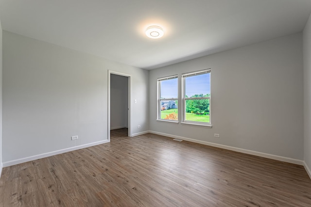 spare room featuring visible vents, baseboards, and wood finished floors