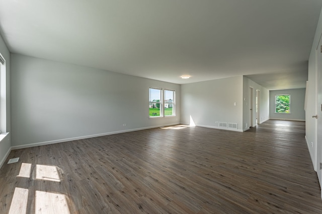 spare room featuring dark wood-style floors, visible vents, and baseboards