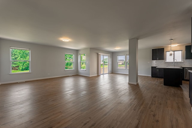 unfurnished living room with dark wood-style flooring, a sink, and baseboards