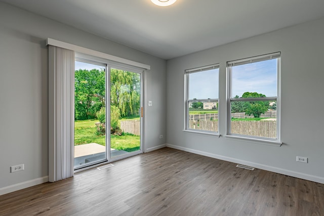 unfurnished room with plenty of natural light, wood finished floors, and visible vents