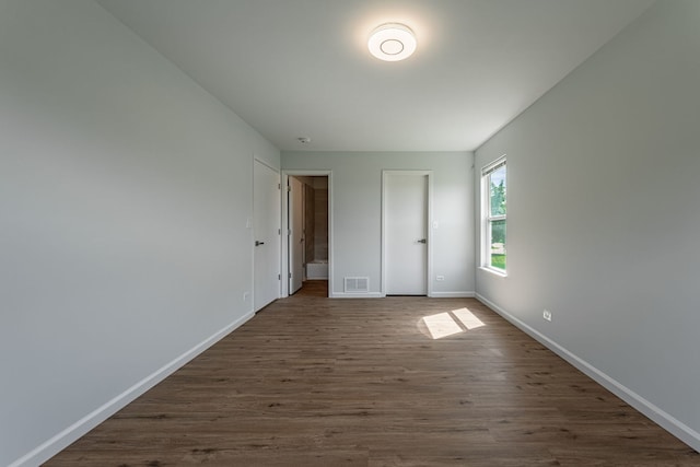 unfurnished bedroom featuring dark wood-type flooring, visible vents, and baseboards