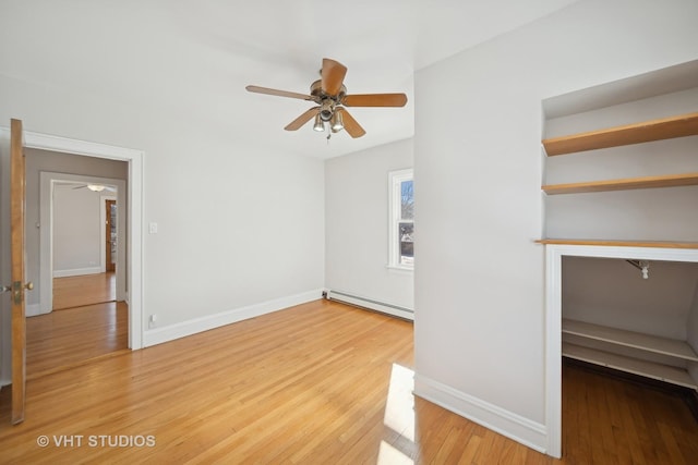 unfurnished living room with light wood-style flooring, a baseboard heating unit, ceiling fan, and baseboards