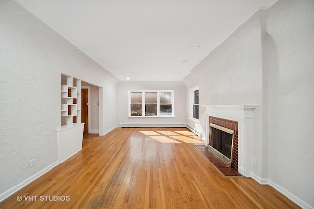 unfurnished living room featuring light wood-type flooring, a brick fireplace, a baseboard radiator, and baseboards