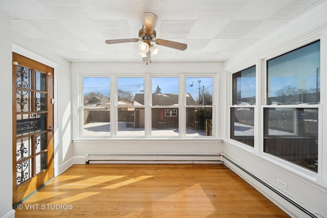 unfurnished sunroom with ceiling fan and a baseboard heating unit