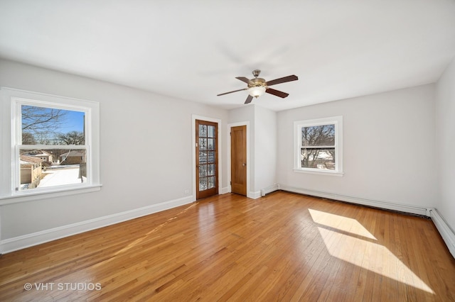 unfurnished bedroom featuring a baseboard heating unit, baseboards, light wood finished floors, and a ceiling fan