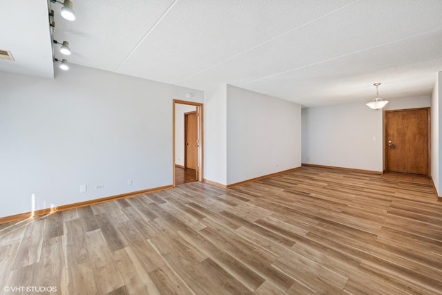 spare room with light wood-type flooring, visible vents, baseboards, and a textured ceiling