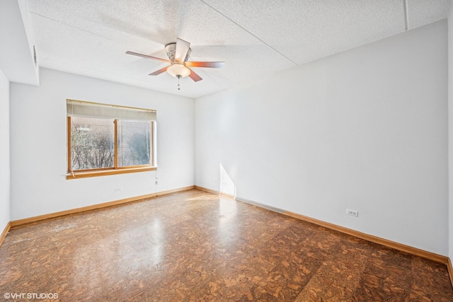 spare room featuring ceiling fan, a textured ceiling, and baseboards