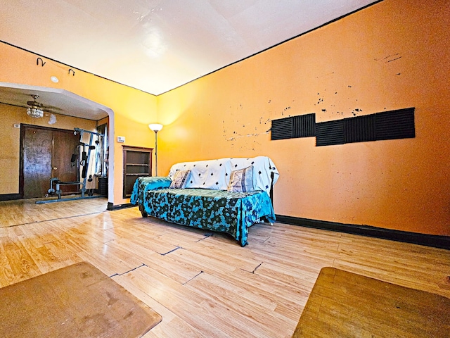 unfurnished bedroom with arched walkways, wood finished floors, and baseboards