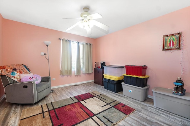 living area with light wood-style floors, baseboards, and a ceiling fan