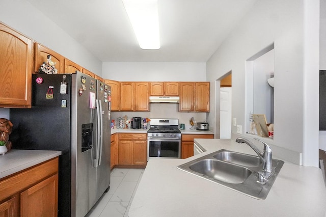 kitchen with under cabinet range hood, a sink, marble finish floor, light countertops, and appliances with stainless steel finishes