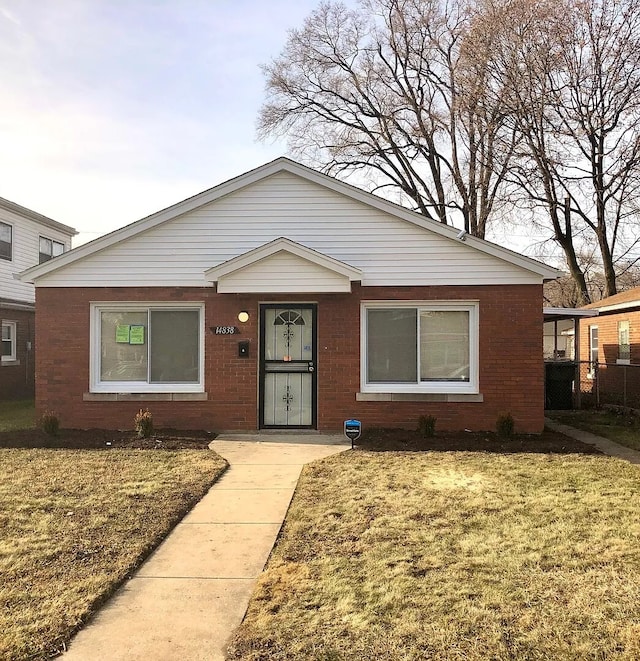 bungalow with brick siding and a front yard