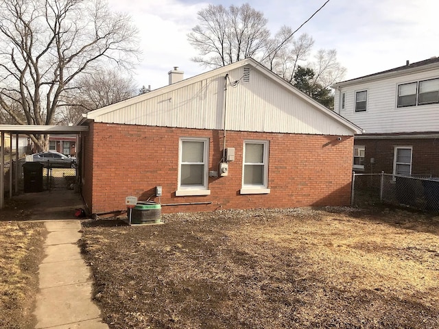 view of property exterior featuring a chimney, brick siding, fence, and central AC