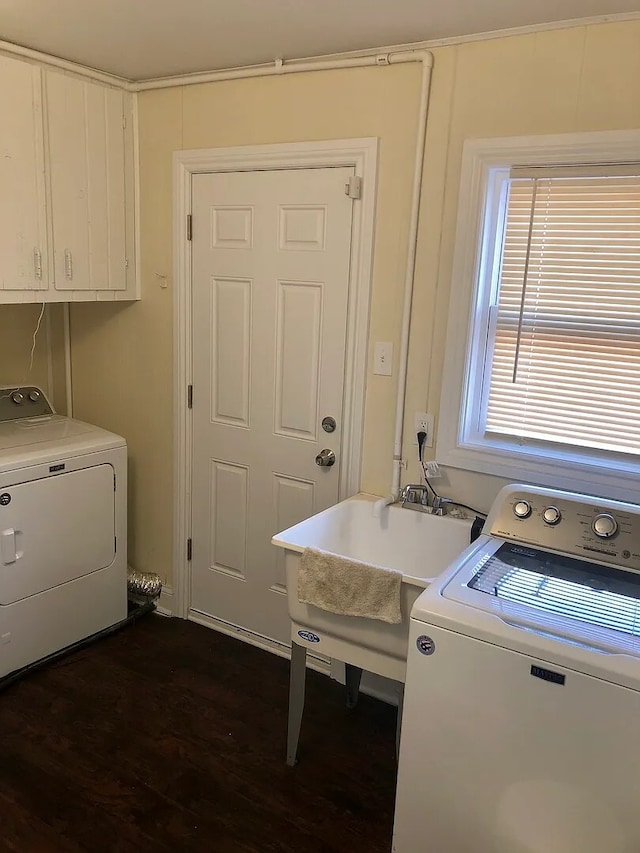 laundry room featuring dark wood-type flooring, cabinet space, a sink, and washing machine and clothes dryer