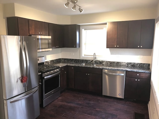 kitchen with dark brown cabinetry, visible vents, dark wood-style flooring, stainless steel appliances, and a sink