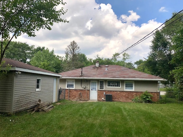 rear view of house with a yard, brick siding, fence, and central air condition unit