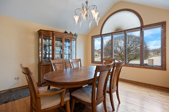 dining room featuring light wood-type flooring, an inviting chandelier, baseboards, and lofted ceiling