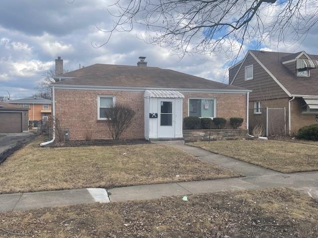 view of front of home with brick siding, a front lawn, and fence