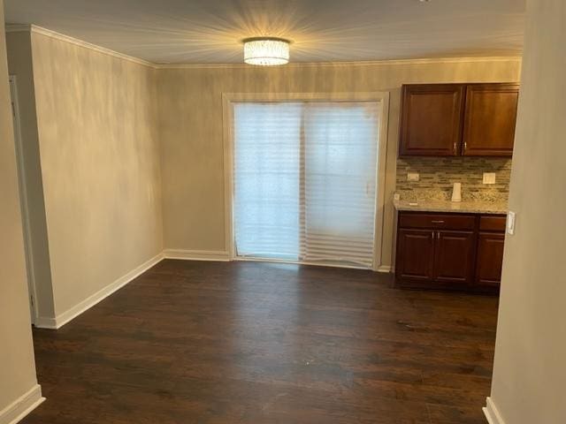 unfurnished dining area featuring dark wood-style floors, baseboards, and crown molding