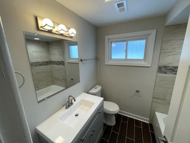 full bathroom with toilet, wood finish floors, vanity, visible vents, and baseboards