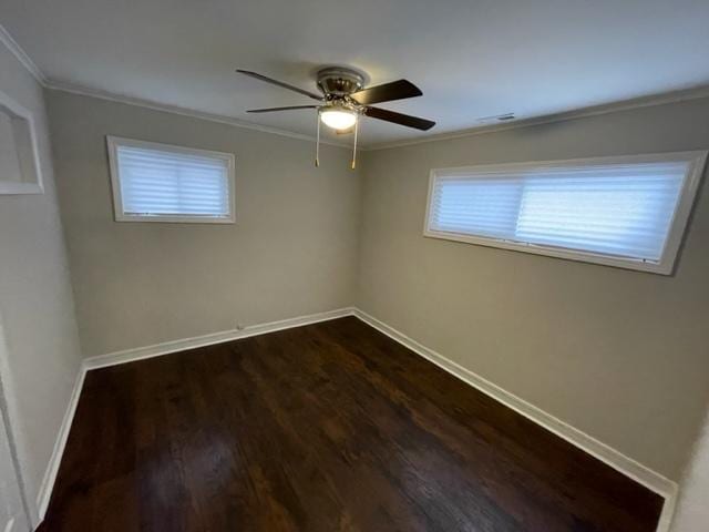 spare room featuring a ceiling fan, baseboards, dark wood finished floors, and crown molding