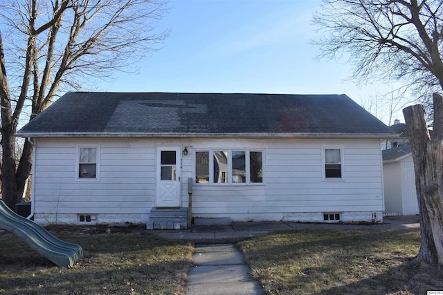 view of front of property featuring entry steps, roof with shingles, and a front lawn