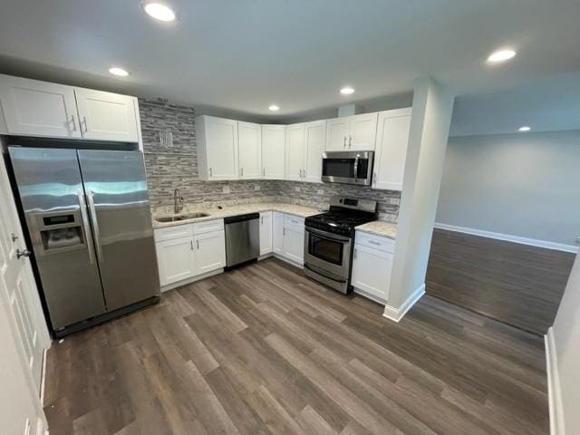 kitchen with dark wood-type flooring, white cabinetry, light countertops, appliances with stainless steel finishes, and tasteful backsplash