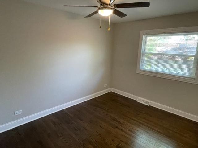 empty room featuring dark wood-type flooring, visible vents, ceiling fan, and baseboards