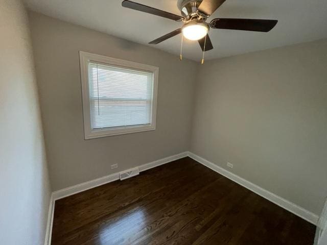 spare room with ceiling fan, visible vents, baseboards, and dark wood-type flooring