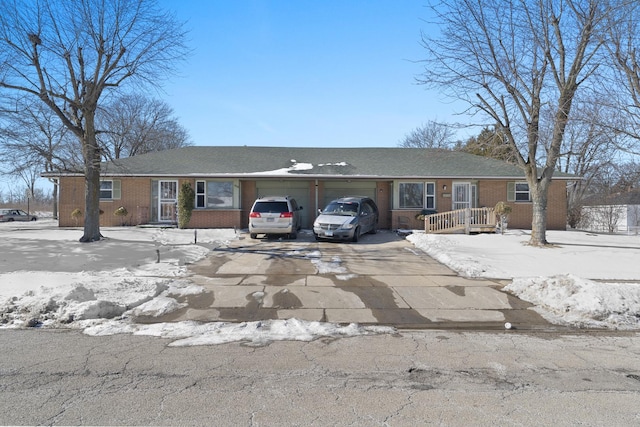 single story home with concrete driveway, brick siding, and an attached garage