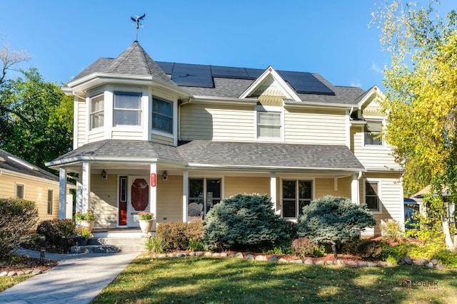 view of front of property featuring covered porch, a shingled roof, and roof mounted solar panels