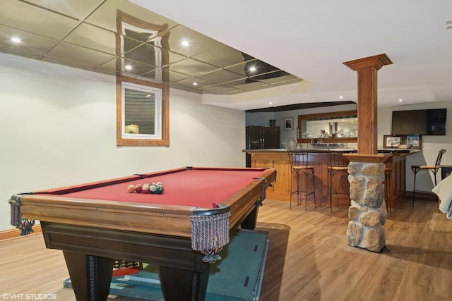 recreation room with recessed lighting, baseboards, light wood finished floors, indoor wet bar, and ornate columns